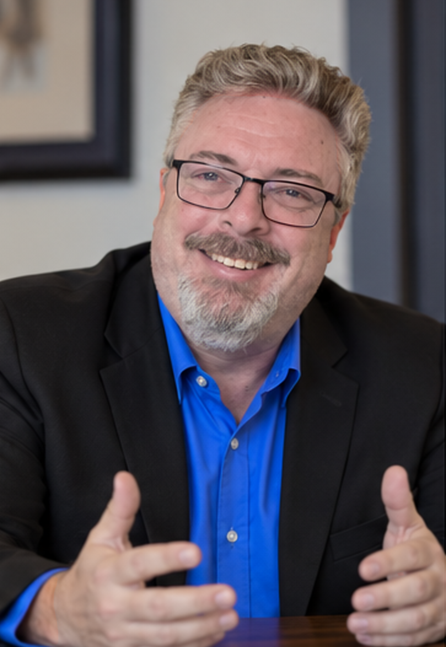 Corey Frasure, mid-sentence, in a blue shirt and dark jacket